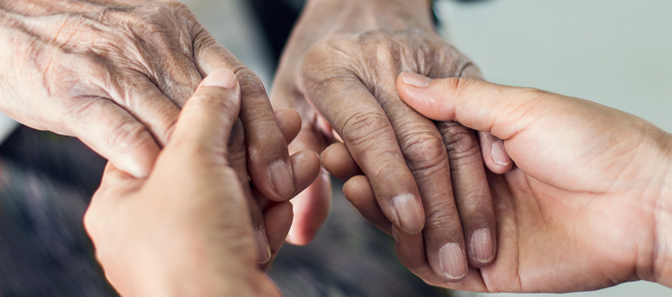Caretaker holding an elderly person's hands