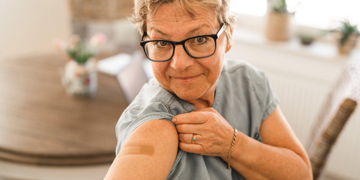 Older woman showing offer the band-aid from her COVID-19 vaccine