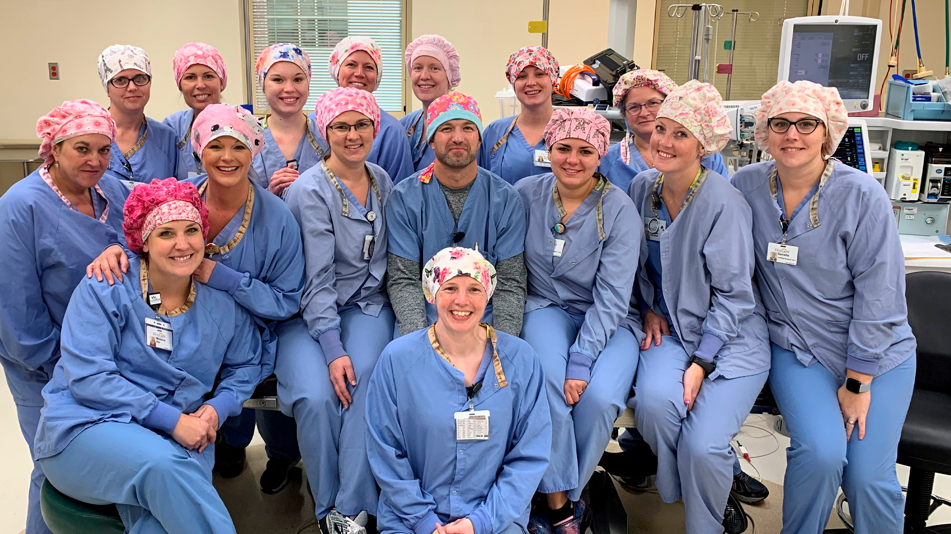Surgery team in the OR all wearing scrubs and pink scrub hats