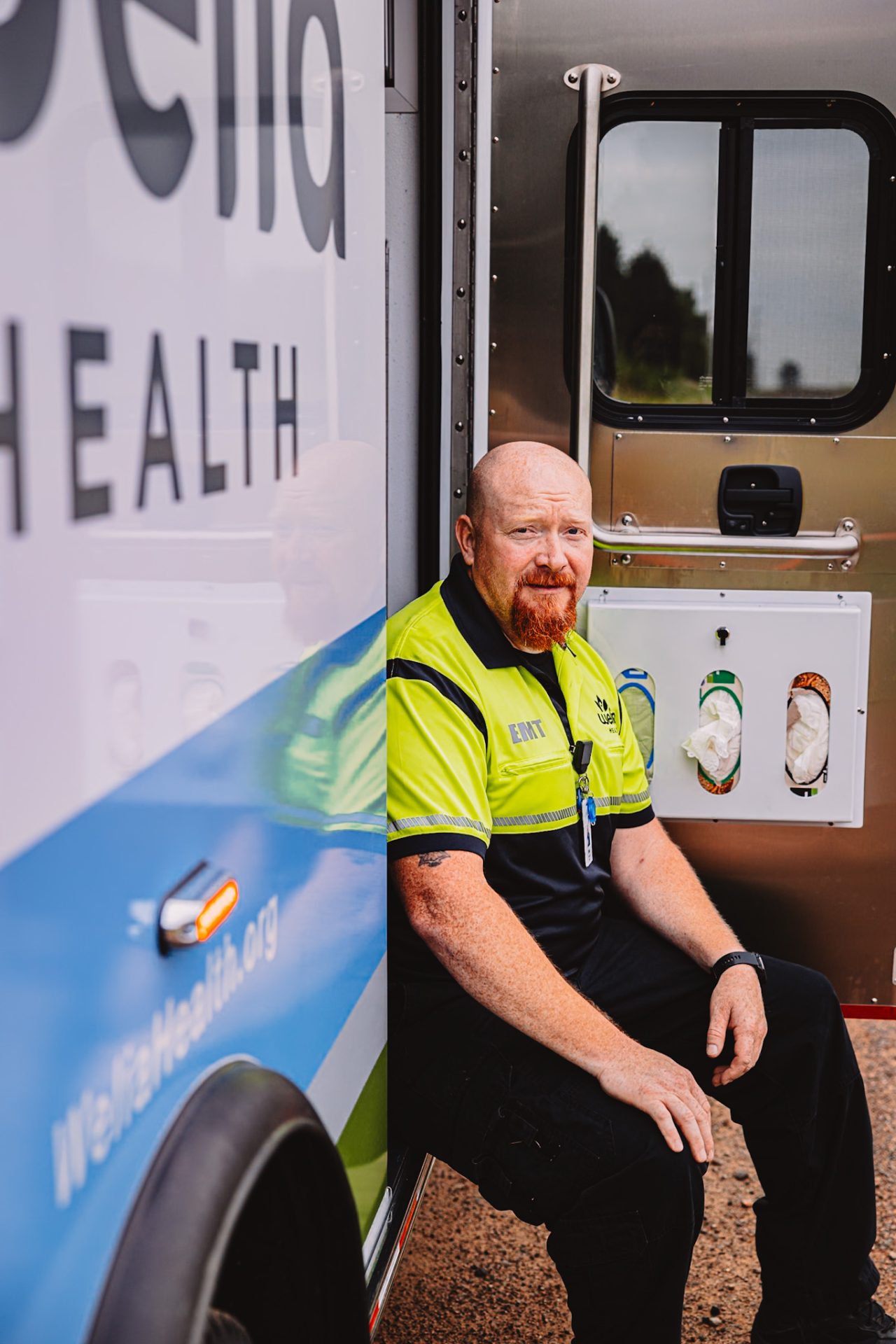 Mike Smith, Welia Health EMT, sitting in the door of an ambulance