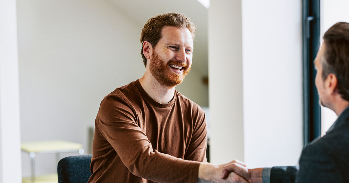 Cheerful bearded man shaking hands with colleague in a bright office setting