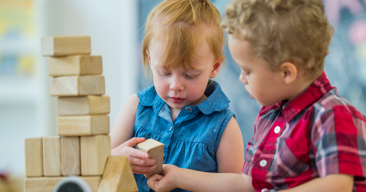 Two toddlers playing with blocks